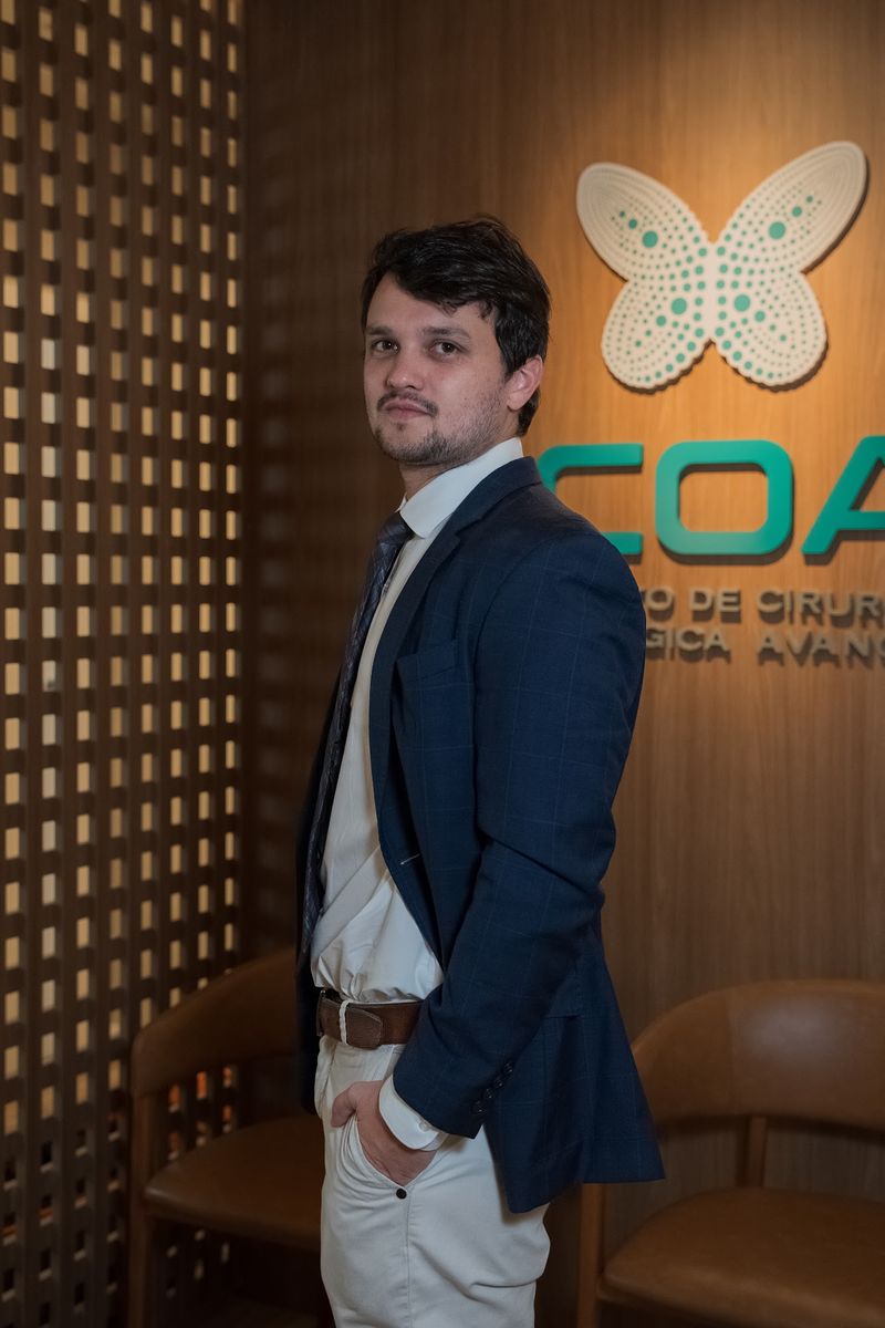 Dr. Mateus Colturato no ICOA, em frente ao painel do instituto